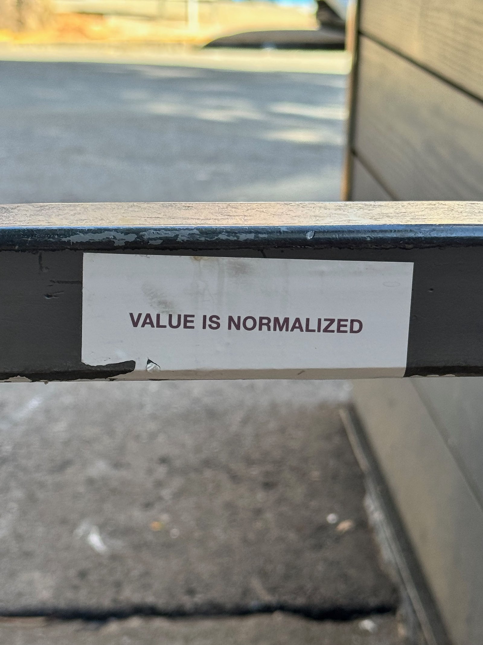 Control Text field test sticker reading “Value Is Normalized” placed on a metal railing in San Francisco.
